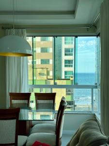 a living room with a table and a view of the ocean at Lindo Apartamento compartilhado vista MAR in Itapema