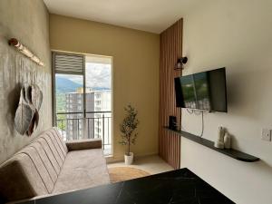 Una sala de estar con un sofá y un televisor de pantalla plana. en Alojamiento Moderno con Parking privado y Ubicación Privilegiada, en Armenia