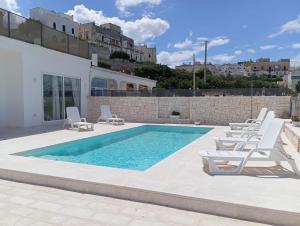 a swimming pool with lounge chairs next to a building at Villa Nunzia in Ostuni