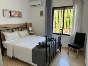 ein Schlafzimmer mit einem Bett und einem Stuhl und einem Fenster in der Unterkunft Villa de los Osos - HUGE 35 PERCENT OFF NOVEMBER SPECIAL - 3min Walk To The Beach & Club De Golf Playa Serena, Entire House, Chalet With XXL Private Pool & Gym in Roquetas de Mar + 60 Fotos