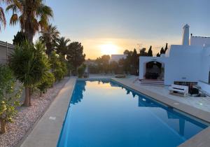 a swimming pool with a sunset in the background at Villa de los Osos - 3min Walk To The Beach & Club De Golf Playa Serena, Entire House, Chalet With XXL Private Pool & Gym in Roquetas de Mar