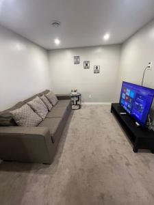 a living room with a couch and a flat screen tv at Cozy Private Suite with Parking near restaurants in Regina