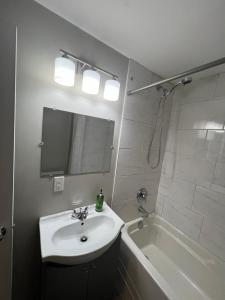 a white bathroom with a sink and a bath tub at Cozy Private Suite with Parking near restaurants in Regina
