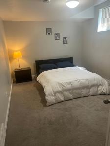 a bedroom with a large bed and a lamp at Cozy Private Suite with Parking near restaurants in Regina
