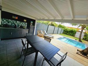 a patio with a table and chairs and a swimming pool at Kaza Lenah villa 2 chambres dont une en mezzanine, piscine et cuve tampon, Saint-François in Saint-François
