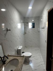 a white bathroom with a toilet and a sink at Casa praia beach place in Luis Correia +3 photos