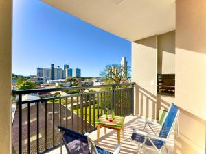 a balcony with a table and chairs and a view of the city at Apartamentos a150 M DA PRAIA com SACADA, WI-FI, PISCINA, PORTARIA 24h, PLAYGROUND e vaga de GARAGEM in Piçarras
