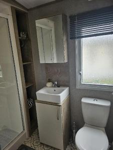 a bathroom with a toilet and a sink and a window at Stunning 6 Berth Caravan Near To The Beach At Pakefield Ref 68115Cr in Lowestoft