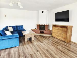a living room with a blue couch and a tv at Domek Zacisze Myśli in Elblag