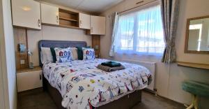 a bedroom with a bed with a comforter on it at Danbury, West Sands Holiday Park in Selsey