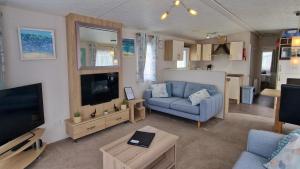 a living room with a blue couch and a television at Danbury, West Sands Holiday Park in Selsey