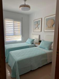 due letti in una stanza bianca con una finestra di Apartamento SERENITY Nerja a Nerja