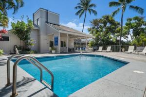 a swimming pool in front of a house with palm trees at Kailua Bay Resort#2-306 in Kailua-Kona