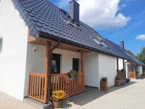 a white house with a black roof at Na Skraju - Pogorzelica - Domki Rekreacyjne lokal D in Pogorzelica