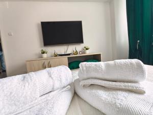 Una sala de estar con televisión y toallas blancas. en Emily Apartment, en Alba Iulia