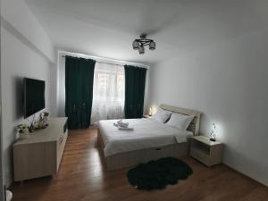 1 dormitorio con cama, TV y cortinas verdes en Emily Apartment, en Alba Iulia