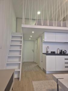 a kitchen with white cabinets and a staircase in a room at Lux Studio Porto in Tivat