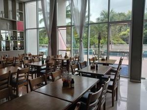 Suíte Confortável no Rio2 - Barra Olímpica RJ في ريو دي جانيرو: مطعم بطاولات وكراسي خشبية ونافذة كبيرة