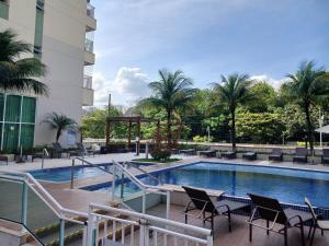 Suíte Confortável no Rio2 - Barra Olímpica RJ في ريو دي جانيرو: مسبح في فندق فيه كراسي ومبنى