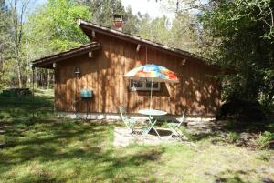 a table and an umbrella in front of a cabin at La Palombière in Saint-Symphorien