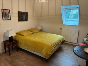 a bedroom with a bed with a yellow bedspread and a window at Belle villa en bord de mer à 700 m d'une plage de sable fin in Combrit