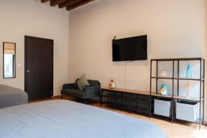 a bedroom with a bed and a chair and a television at 104 Location 2Bdrm 2bath AC apt Fits 8 Rooftop in Mexico City