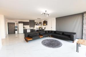 a living room with a black couch and a kitchen at Anamur Deluxe Stone House in Bozdoğan
