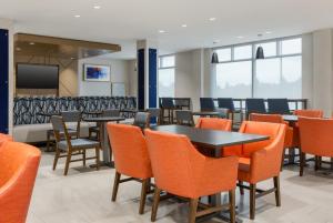 une salle à manger avec des tables et des chaises orange dans l'établissement Holiday Inn Express & Suites Ottawa East-Orleans by IHG, à Ottawa