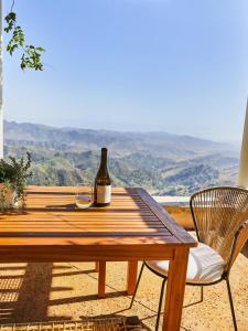 a bottle of wine sitting on a wooden table with a chair at Oja Mountain Ridge in Ojai