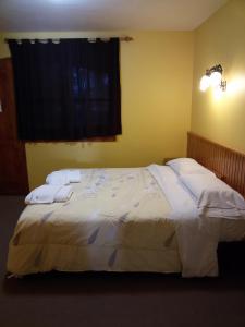 1 dormitorio con 1 cama grande y 2 almohadas blancas en Posada de la Flor en San Carlos de Bariloche