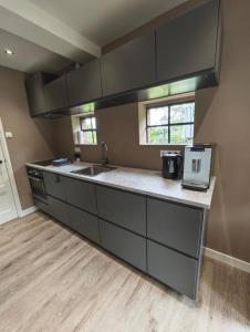 a kitchen with black cabinets and a sink at Vakantiehuisje 'De Uithof' in Oosterhesselen
