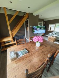 a wooden table with a vase of flowers on it at Vakantiehuisje 'De Uithof' in Oosterhesselen