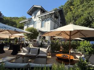 a patio with couches and umbrellas in front of a building at Hotel La Tonnellerie in Spa