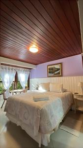 um quarto com uma cama grande e teto de madeira em POUSADA NICO ON THE HILL em Monte Verde mais 114 fotografias