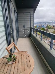 a balcony with a wooden chair and a table at HOM I Vista a la ciudad 4PAX cerca de la Costanera in Puerto Varas