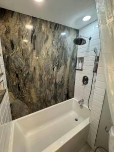 a bathroom with a tub and a stone wall at Skiing, 2 Kitchens, 2 Units in 1, 80in TVs, WD, 2 Backyards in Salt Lake City
