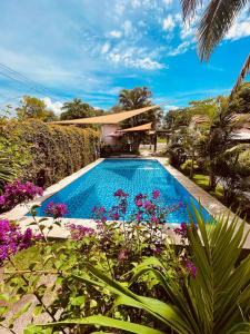 a swimming pool in front of a house with flowers at Copacabana SV L in El Majahual