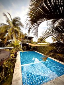 a blue swimming pool with palm trees and a house at Copacabana SV L in El Majahual
