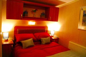 a bedroom with a red bed with two lights on it at Island Bordeaux in Isle of Wight
