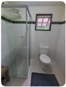 een badkamer met toilet en glazen douche bij Recanto de Gaia in Ilhabela