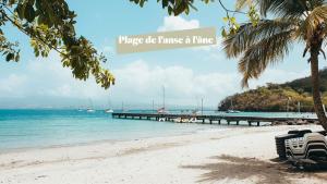 a beach with a pier with boats in the water at KANEL - Votre havre de paix à lAnse Mitan in Les Trois-Îlets