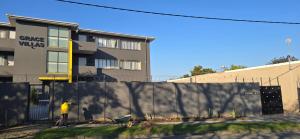 a man standing next to a fence in front of a building at Grace Villas modern studio apartments in East London