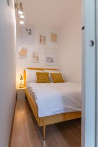 a bedroom with a bed with white sheets and yellow pillows at Apartament HoliStay in Oświęcim