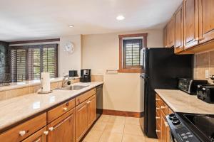 a kitchen with wooden cabinets and a black refrigerator at Lodge Tower 299 One Bedroom Residence in Vail