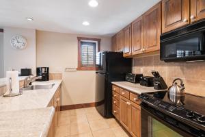 a kitchen with wooden cabinets and a black refrigerator at Lodge Tower 299 One Bedroom Residence in Vail