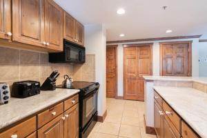 a kitchen with wooden cabinets and a stove top oven at Lodge Tower 299 One Bedroom Residence in Vail +9 photos