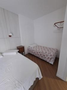 a white bedroom with two beds and a wooden floor at Apartamento no Centro de Brusque/SC in Brusque +10 photos