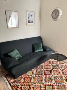 een zwarte bank in een woonkamer met een tapijt bij Le Dany in Saint-Malo