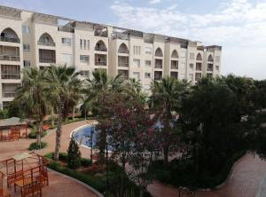 a view of a building with a pool and palm trees at Al-Amaari Gardens Compound 3092 in Irbid