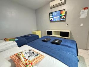 deux lits dans une chambre avec une télévision au mur dans l'établissement Pousada Açude Velho II, à Campina Grande
